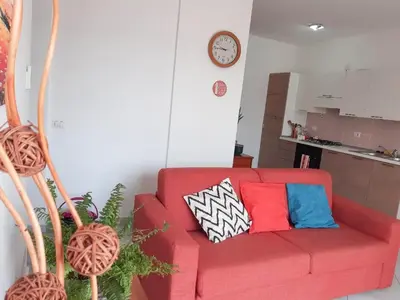 a red couch with colorful pillows in a living room at App Raffaele Estoril Beach Free Wifi & AC a step away from the sea in Sal Rei