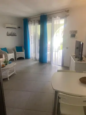 a living room with blue curtains and a television at Apt14 Porto Antigo 1 with Pool and Beach views in Santa Maria