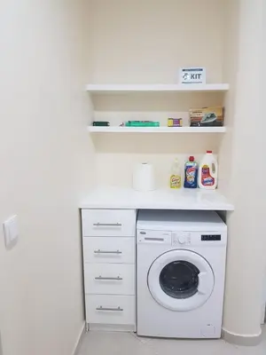 a white laundry room with a washing machine and shelves at Apartamento Teixeira in Espargos