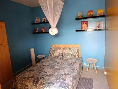 a bedroom with a blue wall with a bed and two stools at Ecolodge Ribeira Principal in Xá Xá
