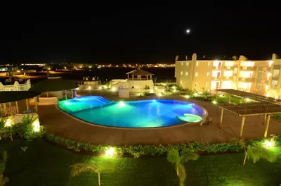 a large swimming pool in front of a hotel at night at Sunset house Cabo Verde in Santa Maria