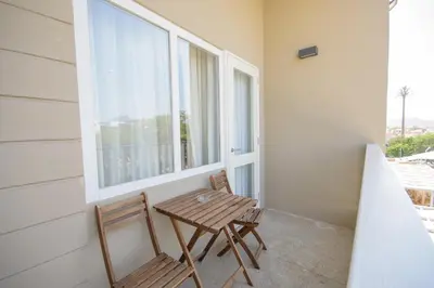 a table and two chairs on a balcony with a window at Oasis Porto Grande in Mindelo