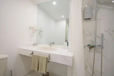 a white bathroom with a sink and a shower at Oasis Porto Grande in Mindelo