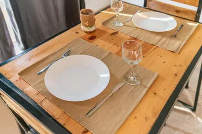 a wooden table with white plates and glasses on it at Apartamento Augusta Amwilla Guesthouse in Mindelo