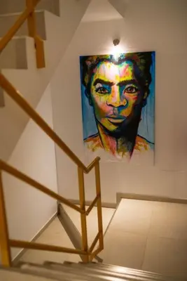 a painting of a woman on a wall next to a staircase at Amwilla Guesthouse Quarto WC privativo Elsa in Mindelo