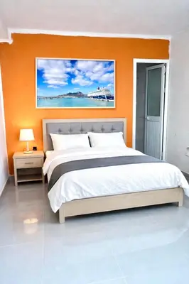 a bedroom with a large bed with an orange wall at Casa BB&Djassi - SUITES in Ponta do Sol