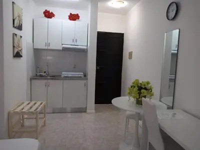 a kitchen with white cabinets and a table and a table and chairs at Ana Place in Praia