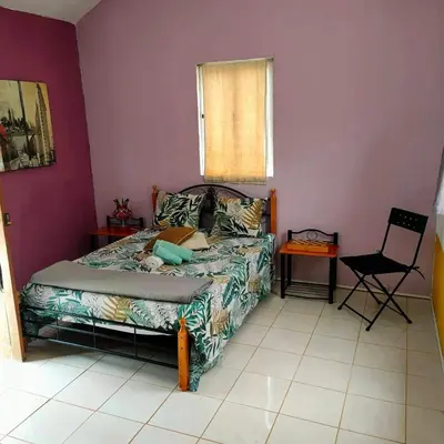a bedroom with a bed and a chair and a window at Tiny House Ribeira Principal in Mato Correia