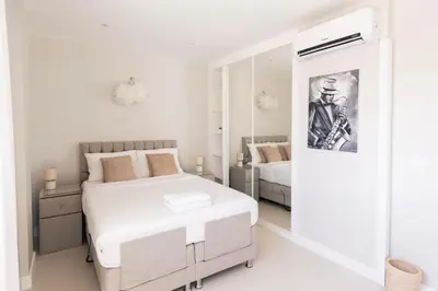 a white bedroom with a bed and a mirror at Penthouse with jacuzzi and sea view, Morabeza Deluxe in Mindelo
