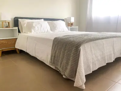 a bedroom with a large bed with white sheets and pillows at Brand New Chic Appt in Mindelo at Great Rates in Mindelo