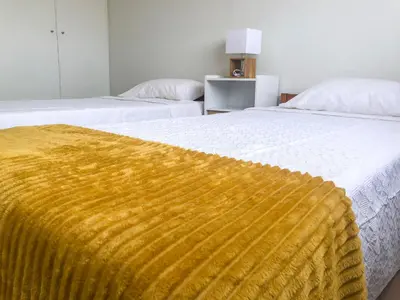 two beds with a yellow blanket on top of them at Brand New Chic Appt in Mindelo at Great Rates in Mindelo