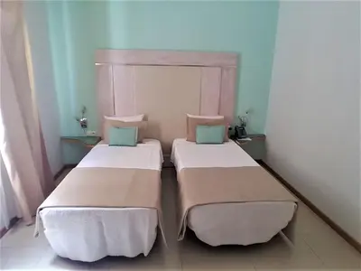 two beds in a small room with blue walls at Sol Hotel in Praia