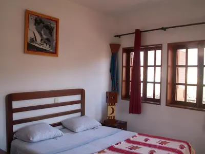 a bedroom with a bed and two windows at Edificio Magico in Tarrafal