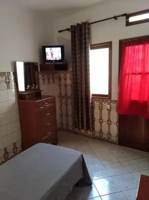 a room with a bed and a tv and a window at Edificio Magico in Tarrafal