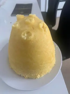 a piece of yellow cake on a white plate at Pam de Terra in Palha Carga