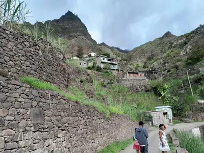 two people walking down a road next to a stone wall at Pousada Rural Simpatia in Caculi