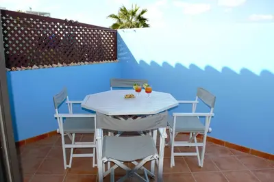 a table and chairs on a balcony with a blue wall at Time Out Pátio Antigo AC Wifi in Santa Maria
