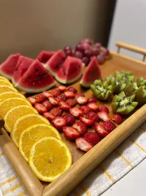 a wooden cutting board with fruit on a table at Apartamentos Avenida in Praia