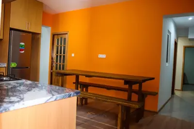 a kitchen with an orange wall and a wooden table at Helton´s Residence in Praia