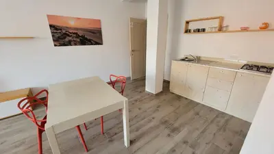 a kitchen with a table and red chairs in a room at Baia Palmeira Residence in Palmeira