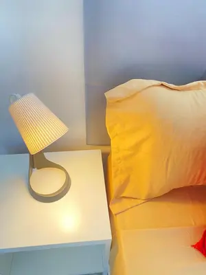 a lamp on a table next to a bed with a pillow at Best Rooms- Quarto 4 Plateau in Praia