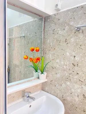 a bathroom with a sink and a vase with orange flowers at Best Rooms- Quarto 4 Plateau in Praia