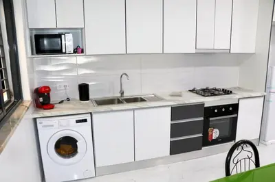 a white kitchen with a washing machine and a microwave at Figo Apartamentos Cidadela Comfort Flats in Praia