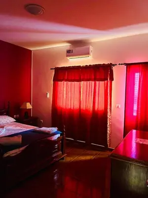 a red room with two beds and a window with red curtains at Casa BB&Djassi - ROOMS in Ponta do Sol