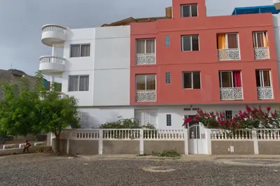 a red and white building with a white fence at Apart Laginha Tess & To in Mindelo