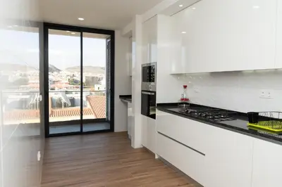 a white kitchen with a view of a balcony at 3 bdr aprt, best seaview, rooftop pool - LCGR in Praia