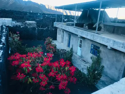 a house with red flowers on the side of it at Pensão Repouso Alegre Turismo e Aventura in Portela