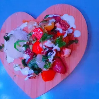 a pink heart shaped plate of food on a blue background at Splanada poilon in Assomada