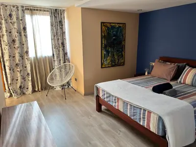 a bedroom with a bed and a chair and a window at Orietta Residencial in Mindelo