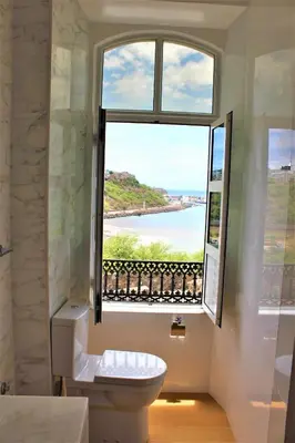 a bathroom with a toilet and a large window at KAZARÃO DI MAVETE- Guesthouse in Praia