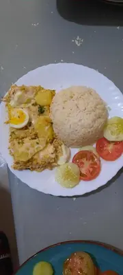 a plate of food with eggs and rice and tomatoes at My Flat 1 in Praia