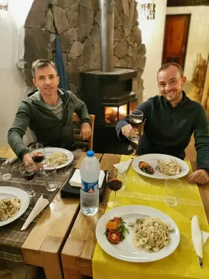 two men sitting at a table with plates of food at Strela Mountain Lodge in Tarrafal