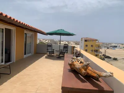 a table on the balcony of a house with an umbrella at Spacious Penthouse with Sea View - Boteto U in Sal Rei