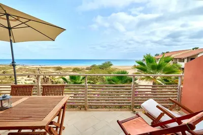 a patio with a table and chairs and the beach at Corallo Beach Front Apartments - By Bobbywashere in Santa Maria