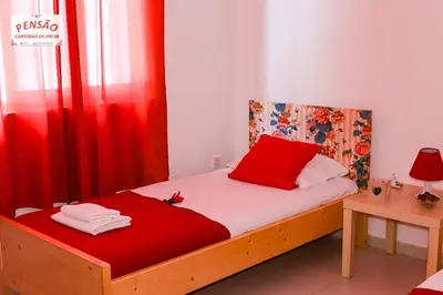 a bedroom with a bed with red sheets and a red curtain at Pousada Cantinho de Preta in Seladinha