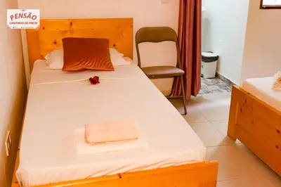 a bedroom with a bed with a towel and a chair at Pousada Cantinho de Preta in Seladinha