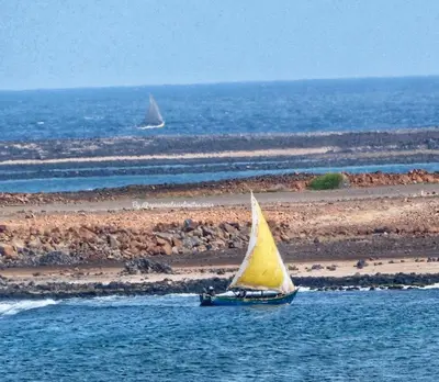 a small boat with a yellow sail in the water at Beach house kasa Sala mansa in Salamansa