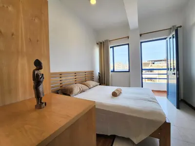 a bedroom with a large bed and a large window at Txada Hostel in Praia