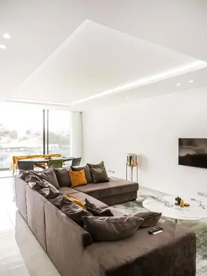 a living room with a brown couch in a white room at Filomena Apartments LUXURY in Mindelo