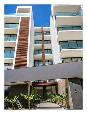 a large white building with palm trees in front of it at Filomena Apartments LUXURY in Mindelo