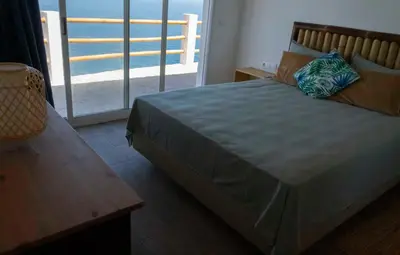 a bedroom with a large bed and a balcony at RM Green Hotel in Lombo Branco