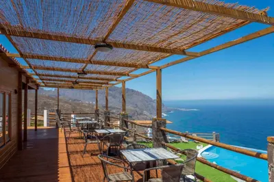 a deck with tables and chairs and the ocean at RM Green Hotel in Lombo Branco