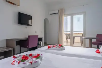 a room with two beds with a desk and a balcony at VOI Praia de Chaves Resort in Sal Rei