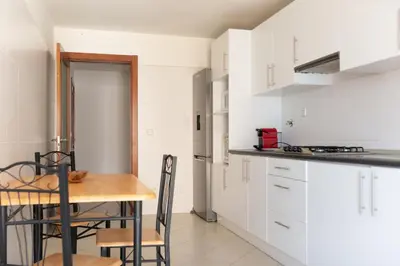 a kitchen with white cabinets and a table and chairs at 2 bdr cozy beachside apartment, Copacabana - LCGR in Mindelo
