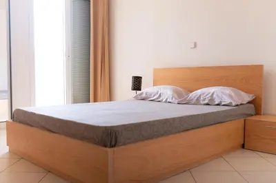 a bedroom with a large bed with a wooden headboard at 2 bdr cozy beachside apartment, Copacabana - LCGR in Mindelo