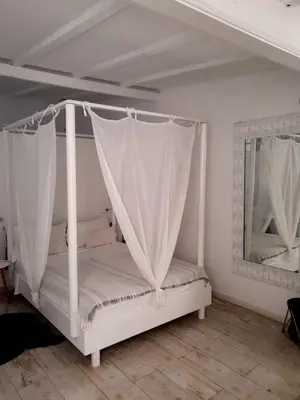 a white bed with a canopy in a room at As Hortênsias in Mindelo